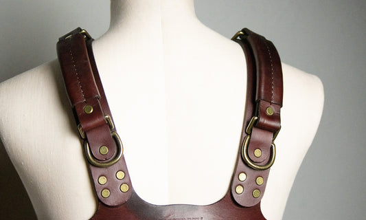 The Oliver leather bondage harness is pictured from the back, where the straps that go over the shoulder connect securely to the strap that encircles the ribcage. Each shoulder strap of this bondage harness has a strong leather suitcase handle for rough play added. 