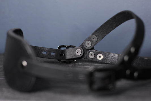 A side view of the black metal hardware on the leather blindfold.