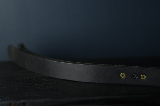 A closeup of the grip of the bdsm leather impact toy. Two rivets hold the three straps in place for secure impact play.