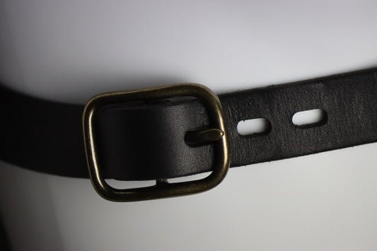 A closeup of the brass buckle on this black leather harness. 