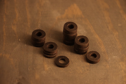 several piles of leather washers for DIY leather crafting and DIY bdsm are pictured. These leathercraft washers are ideal for durable but flexible leather DIY projects.  
