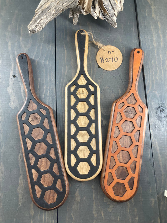 Three oak spanking paddles with leather inlays are displayed side by side.