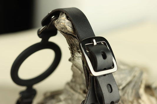 A closeup of the black leather head harness's hardware, which demonstrates an adjustable black buckle. 